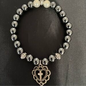 Bead Bracelet With a Heart Shaped Charm Featuring a Cross.